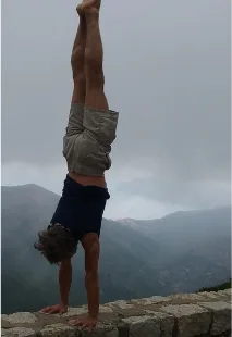 Philippe en équilibre sur les mains, au bord d’un muret, devant des montagnes