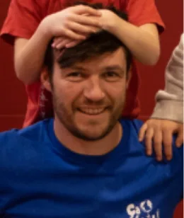 Stéphane, souriant, des mains d’enfant posées sur sa tête